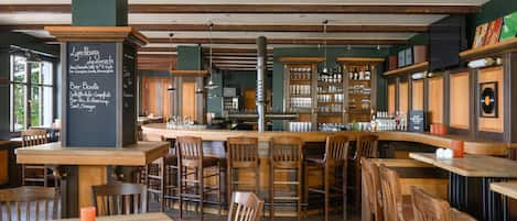 Un restaurante acogedor con mobiliario de madera, un menú en una pizarra y una zona de bar.