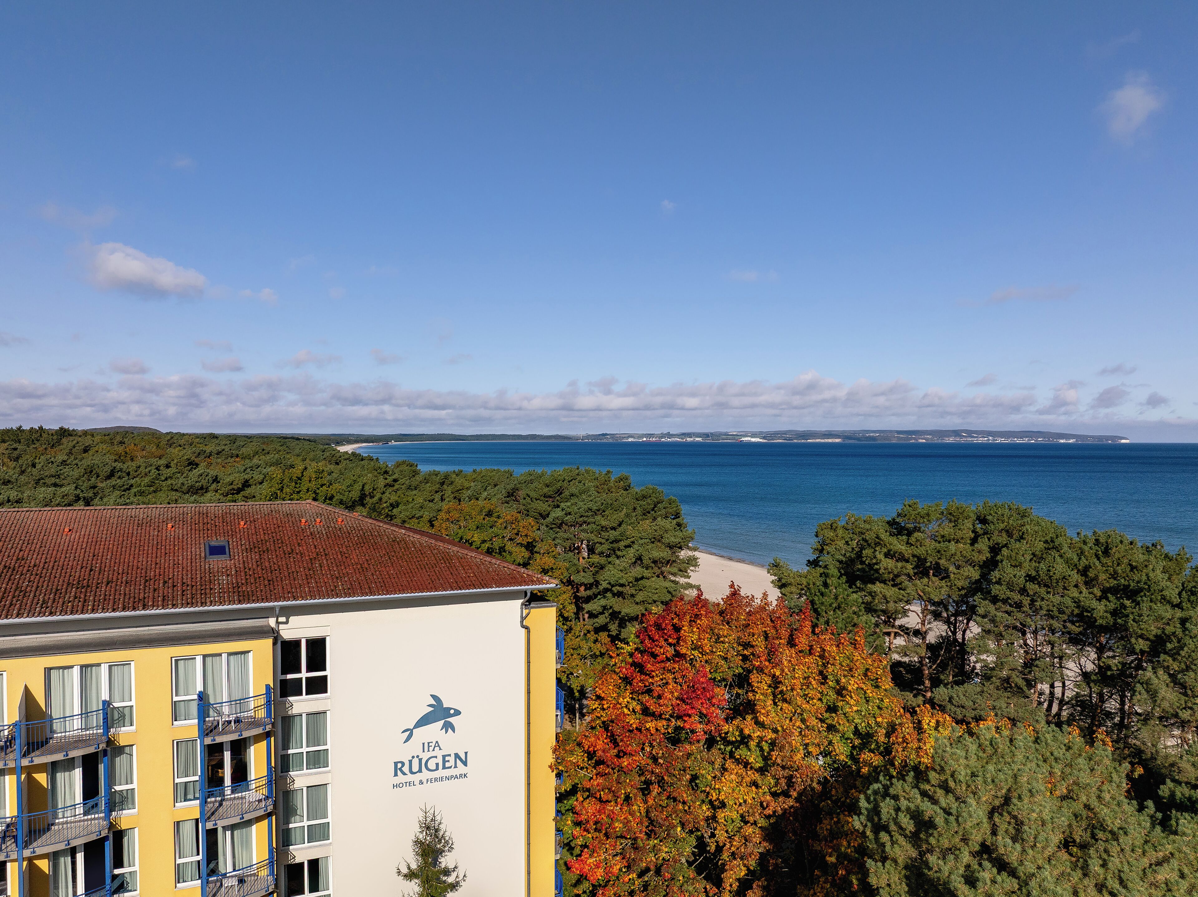 A hotel with a view of the sea and autumn foliage.