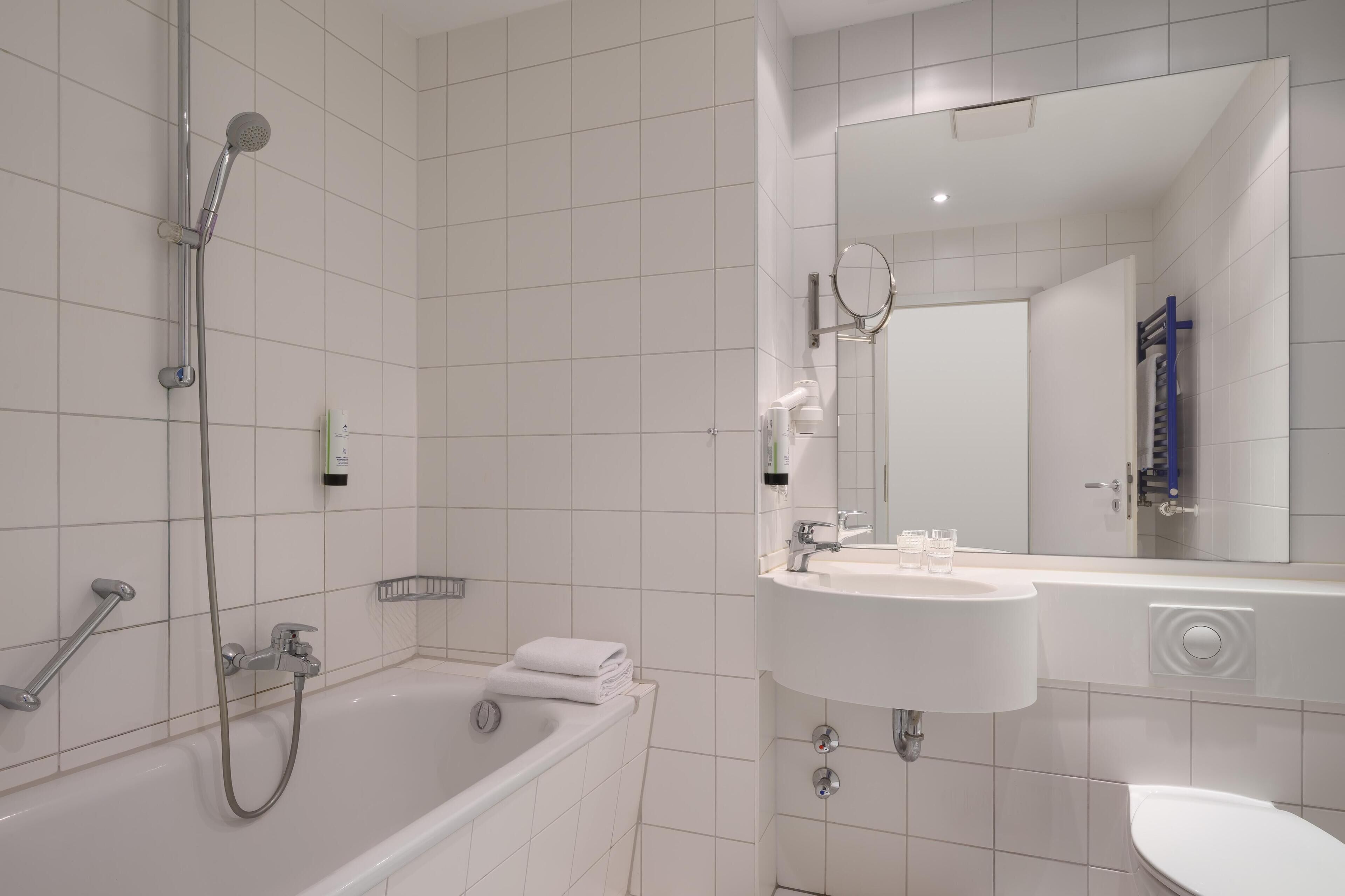 Een moderne badkamer met een bad, douche, wastafel en toilet.