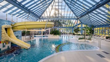 Een binnenzwembad, ligstoelen bij het zwembad