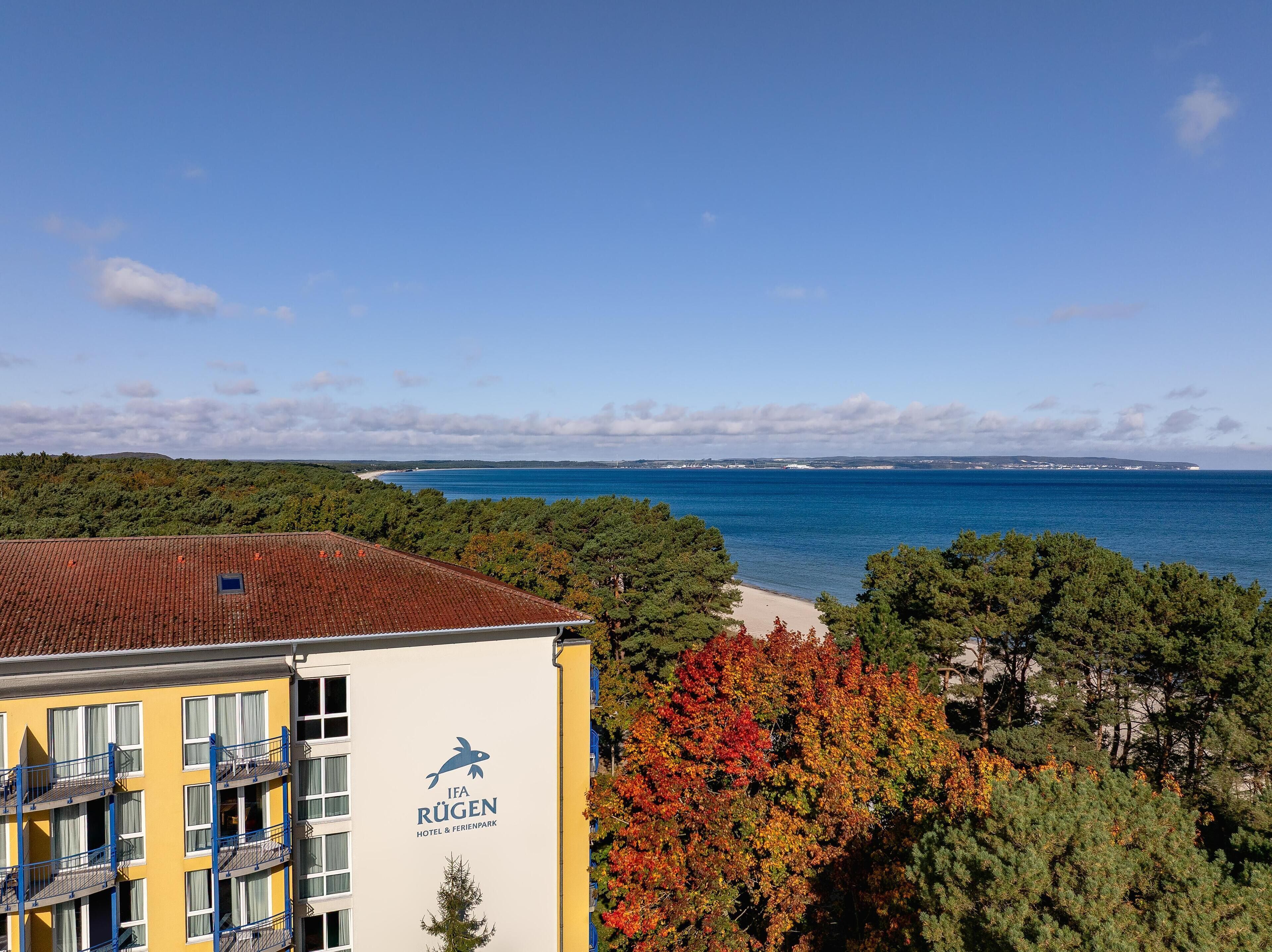 A hotel with a view of the sea and autumn foliage.