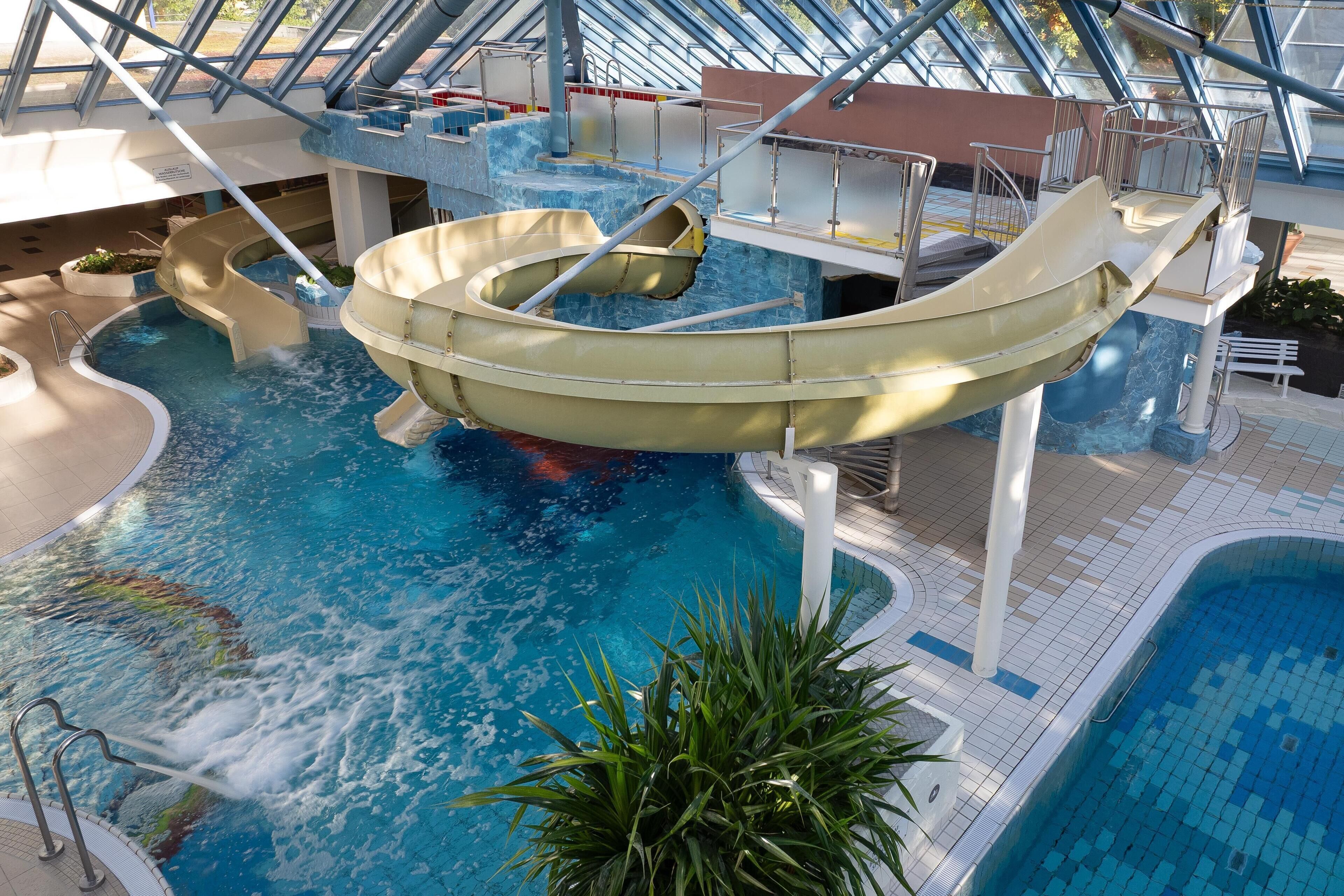 Ein Wasserpark mit mehreren Rutschen und Pools, darunter eine große Zentralrutsche und ein kleinerer Poolbereich.