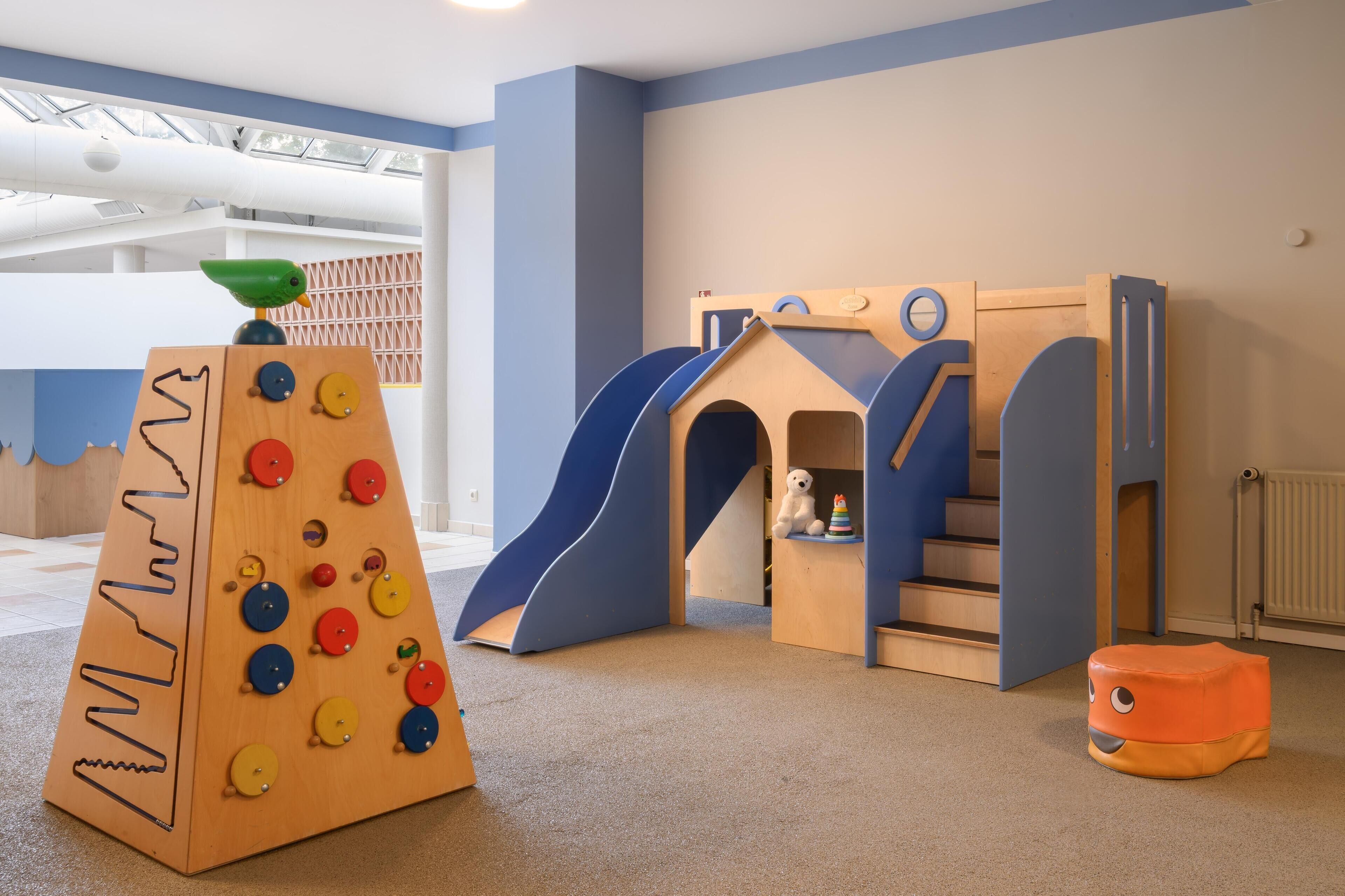 Un área de juegos con una estructura para escalar, un tobogán y una casita.