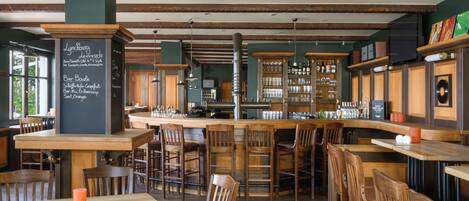 A restaurant interior with wooden tables and chairs, a bar area, and a chalkboard menu.