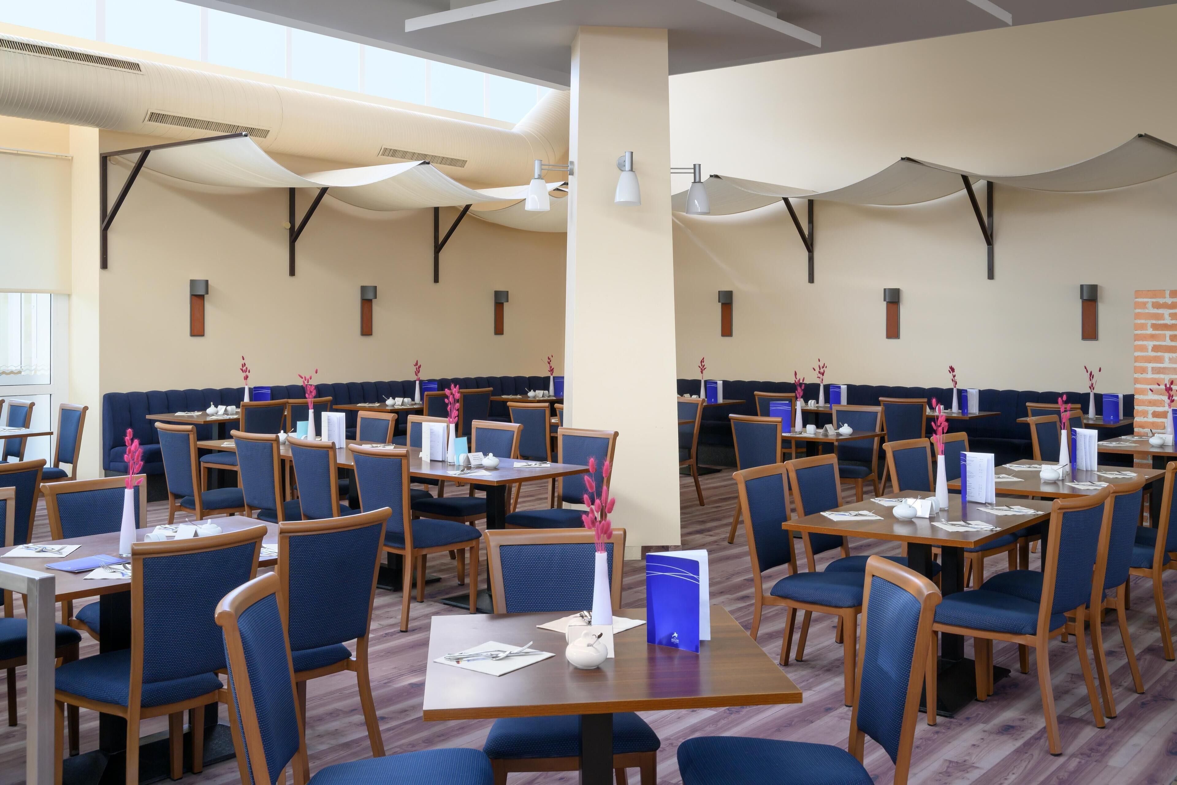 A dining area with tables and chairs, some with menus and decorative items.