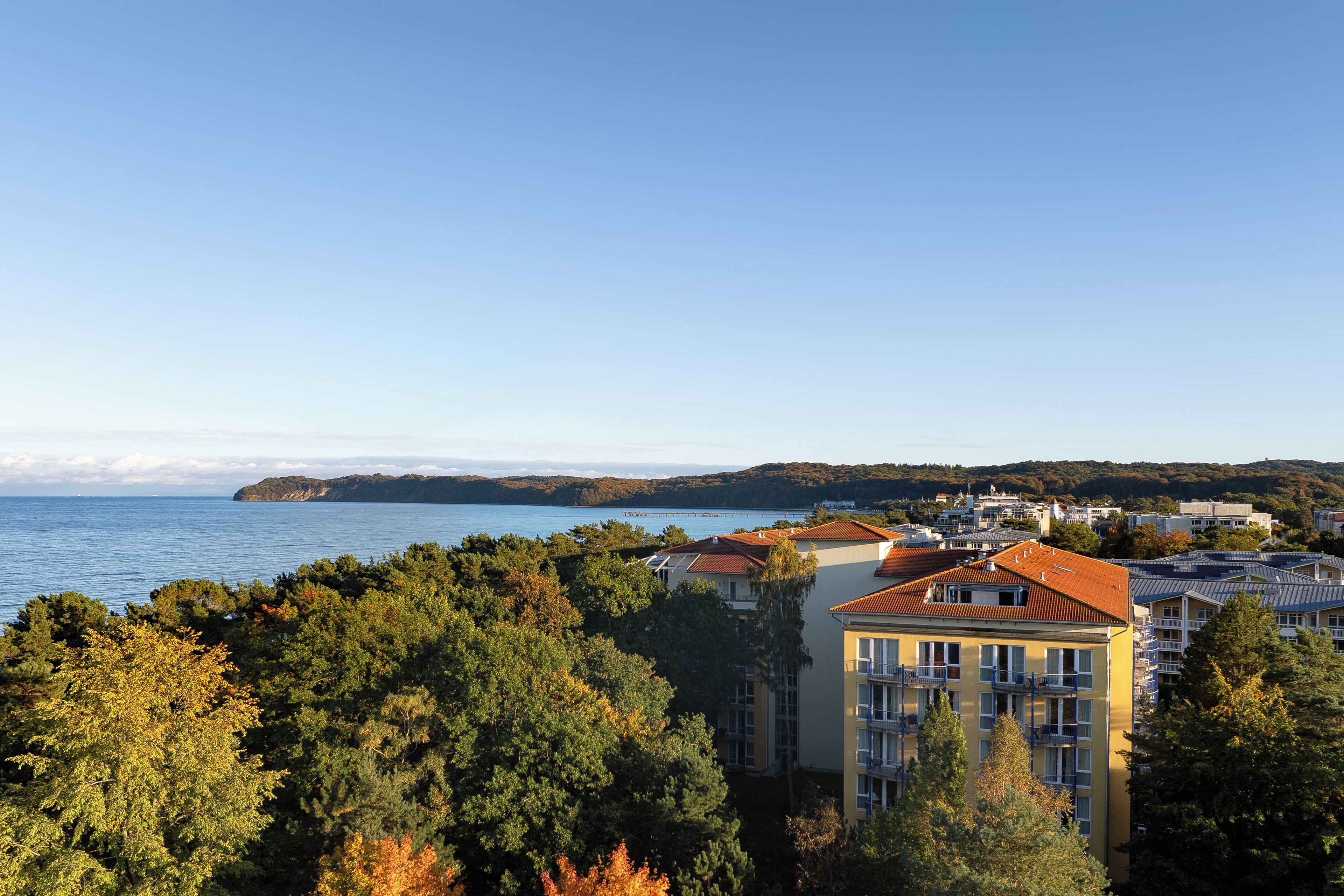 A coastal residential area with buildings, trees, and a view of the sea.
