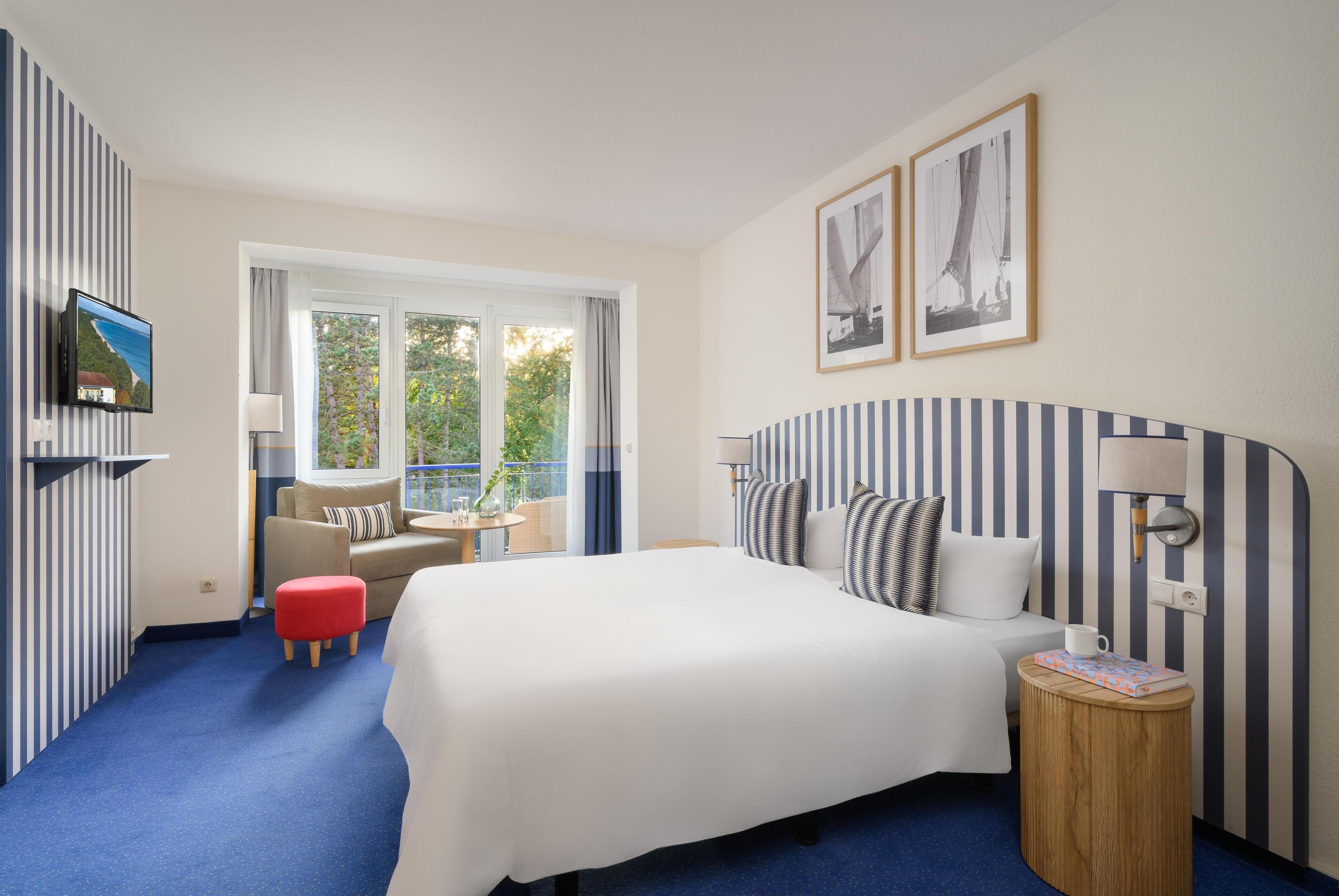 A hotel room with a large bed, a sofa, a small table, and a TV.