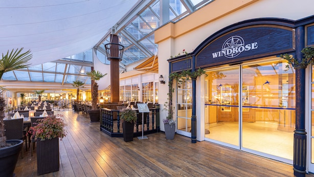 A spacious indoor area with a wooden floor, a glass ceiling, and a store named Windrose. - IFA Fehmarn Hotel & Ferien-Centrum (Fehmarn)