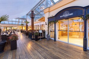 A spacious indoor area with a wooden floor, a glass ceiling, and a store named Windrose. - IFA Fehmarn Hotel & Ferien-Centrum (Fehmarn)