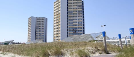 A coastal walkway leading to modern high-rise buildings with a clear sky.