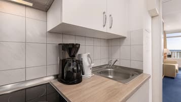 A modern kitchen with a coffee maker, kettle, and sink.
