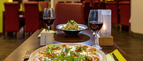 A restaurant setting with a pizza and wine glasses on a table.