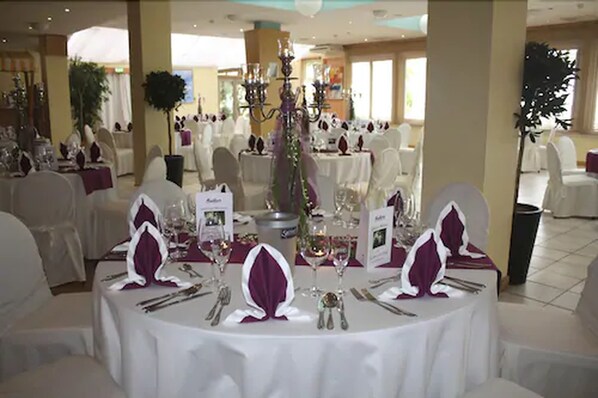 A banquet hall with round tables set for a formal event, featuring white tablecloths, purple napkins, and silverware. - IFA Fehmarn Hotel & Ferien-Centrum (Fehmarn)
