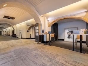 Un moderno vestíbulo de hotel con mostrador de recepción, zona de estar y obras de arte en las paredes.