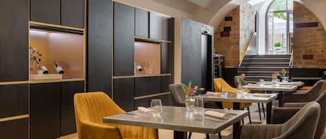 Un espace repas moderne avec de hautes tables, des chaises confortables et une vue sur l’escalier extérieur.