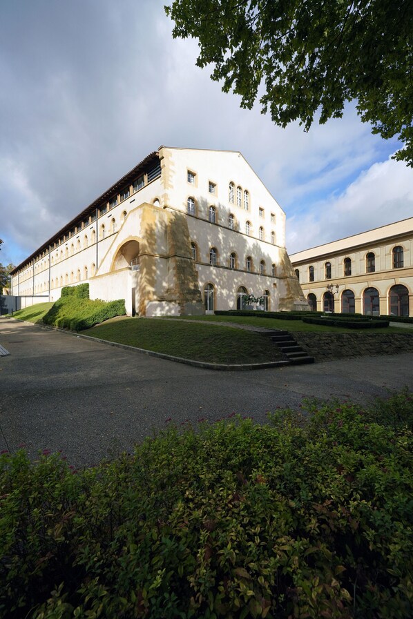 A large, historic building with a central courtyard, arched windows, and a stone staircase leading to an upper level.