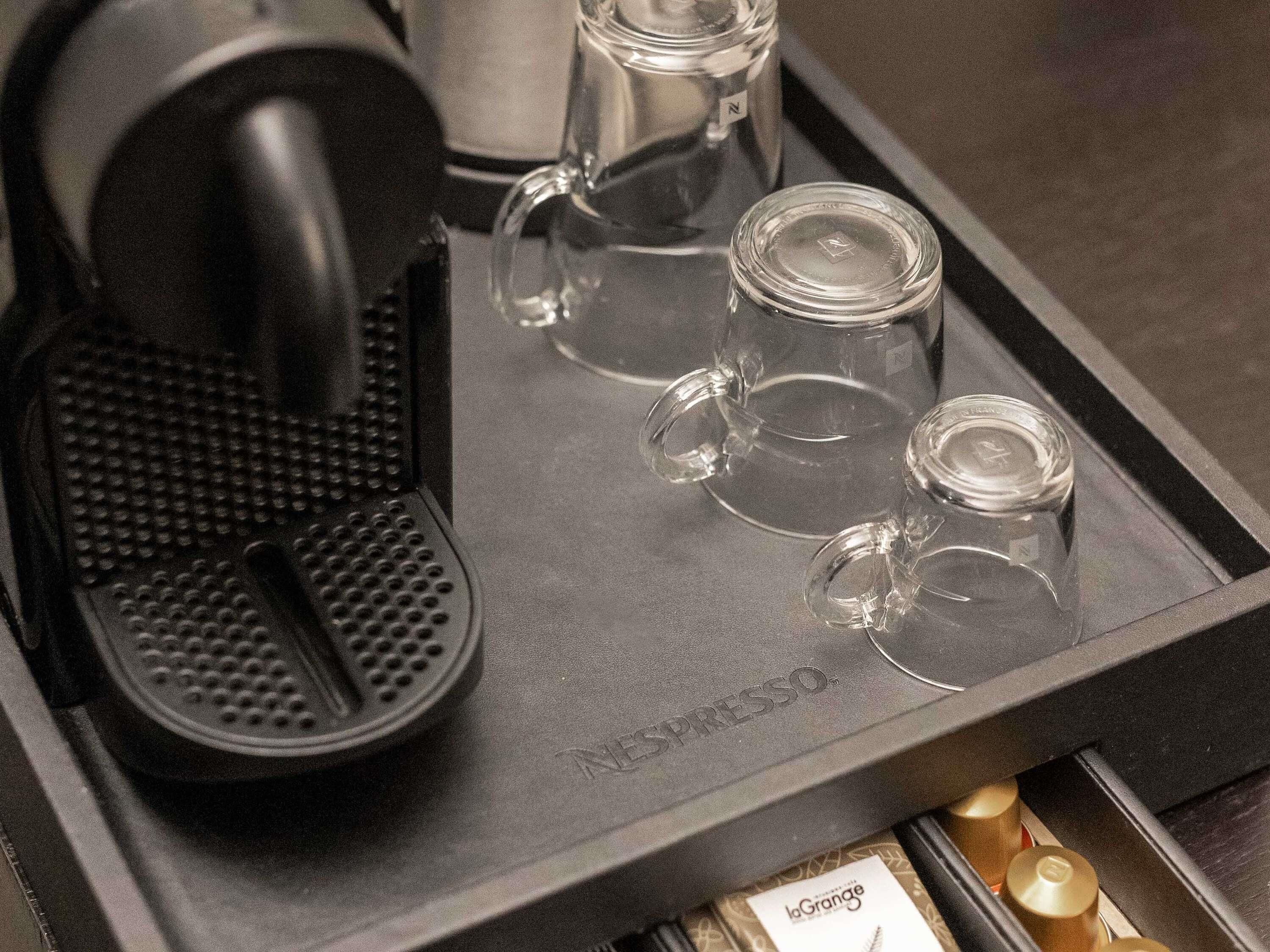 Una cafetera y cuatro tazas de vidrio sobre una bandeja.