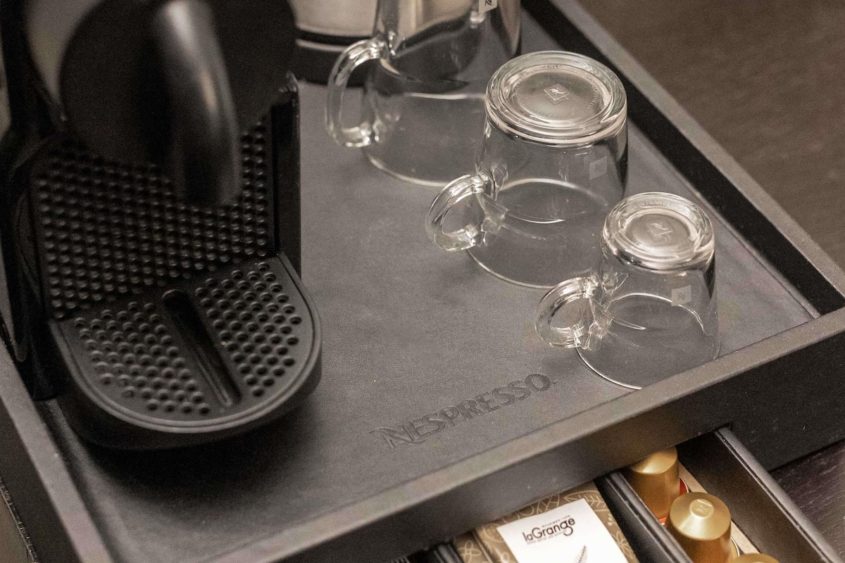 Una cafetera y cuatro tazas de vidrio sobre una bandeja.