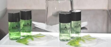 Una encimera de baño con tres botellas de champú Anezzi Towel y un recipiente de vidrio.