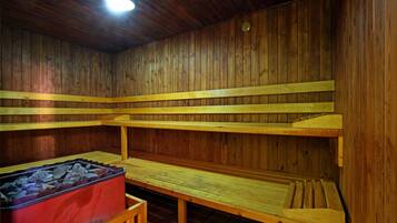 Een sauna met houten banken en een rode infraroodbank.