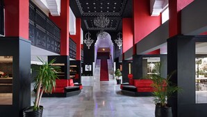 A modern lobby with a central staircase, black and red walls, and potted plants. - Anezi Tower Hotel (Agadir)