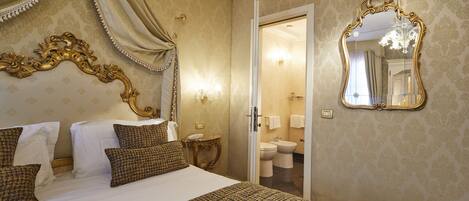 Habitación de hotel con una cama grande, un espejo y un baño visible a través de una puerta abierta.