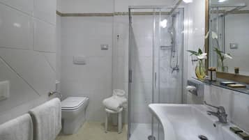 Un baño moderno con cabina de ducha de vidrio, un lavabo blanco y un inodoro.