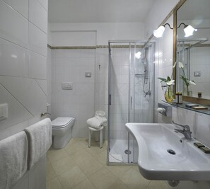 A modern bathroom with a glass shower enclosure, a white sink, and a toilet.