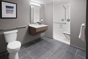 A modern bathroom with a toilet, vanity, mirror, shower, and tiled floor.
