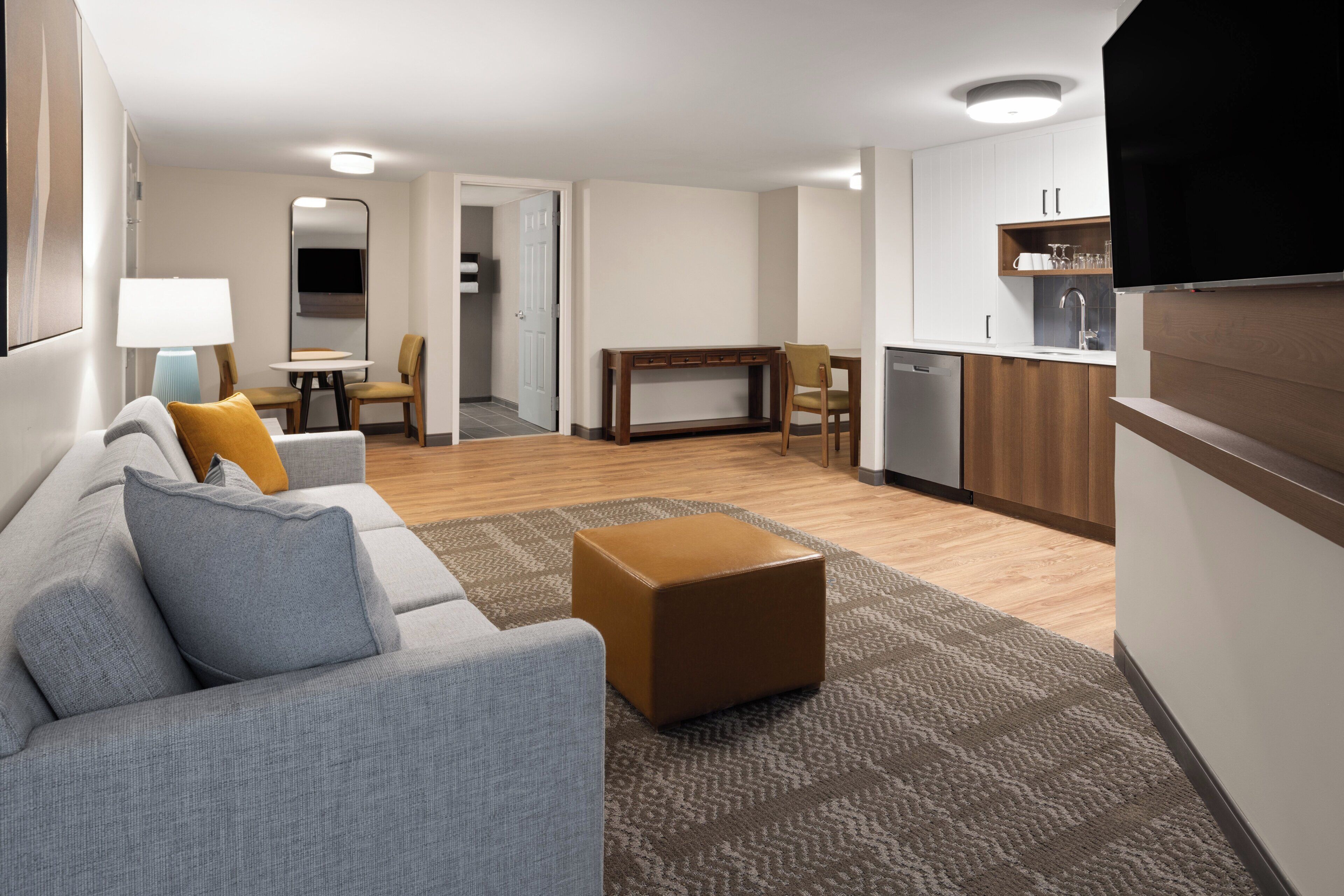 A modern living room with a grey sofa, a coffee table, and a dining area with a table and chairs.