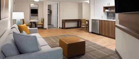 A modern living room with a grey sofa, a coffee table, and a dining area with a table and chairs.