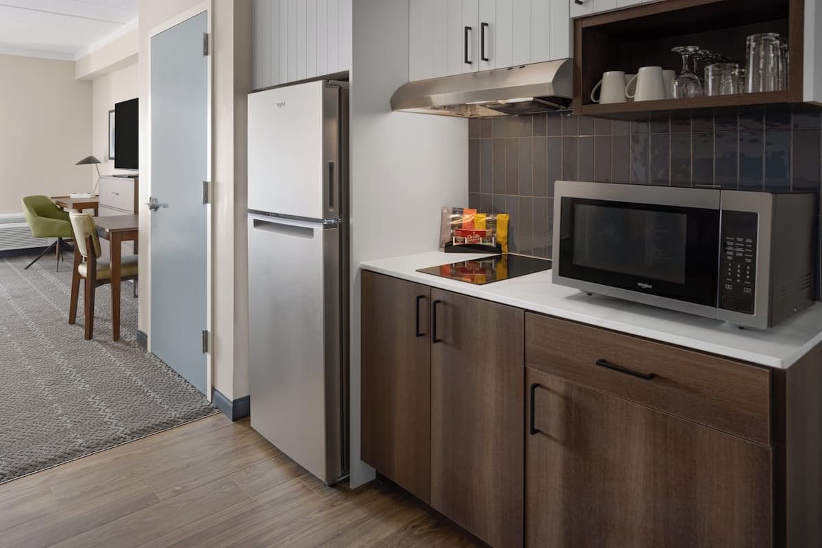 Una cocina moderna con microondas integrado, refrigerador y armarios de madera.
