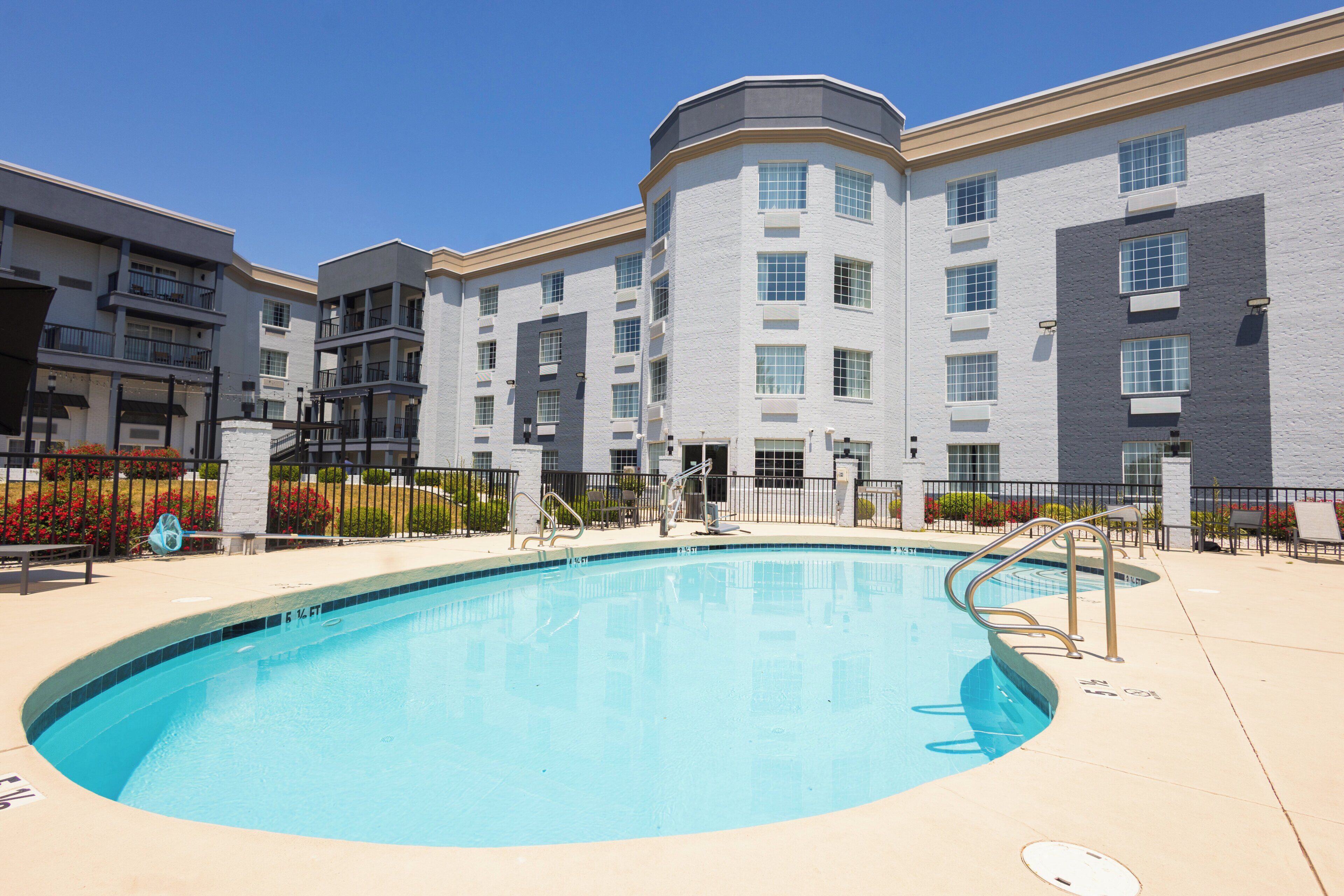 A swimming pool with steps, surrounded by a building with multiple balconies and windows.