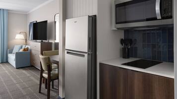 A modern kitchen with a refrigerator, microwave, and a dining area with a table and chairs.