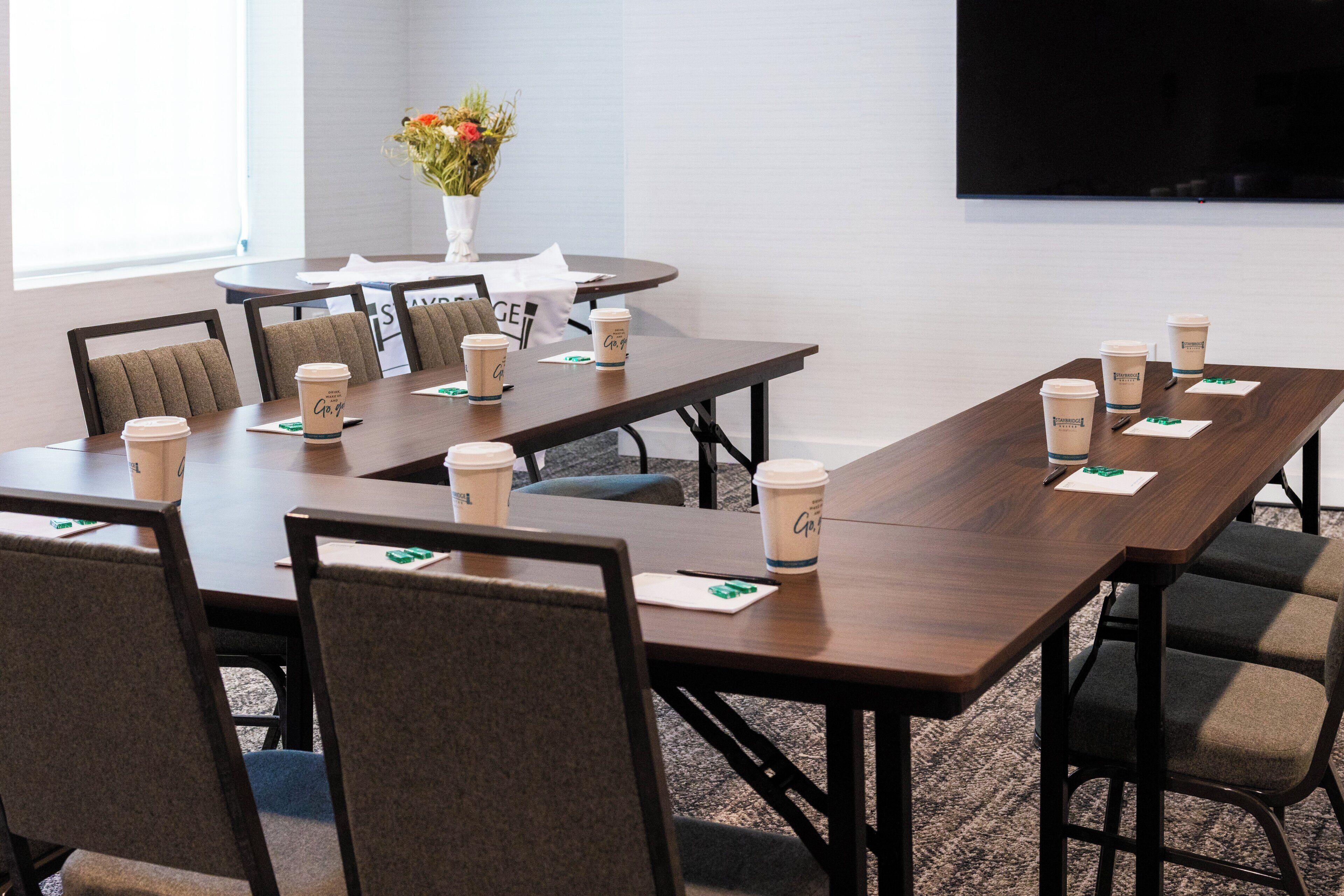 A conference room with a long table, multiple chairs, and coffee cups.