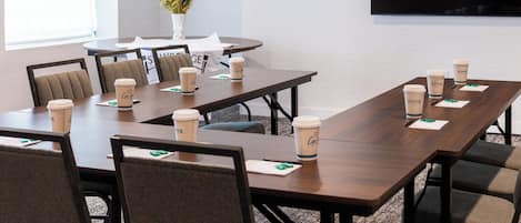 A conference room with a long table, multiple chairs, and coffee cups.