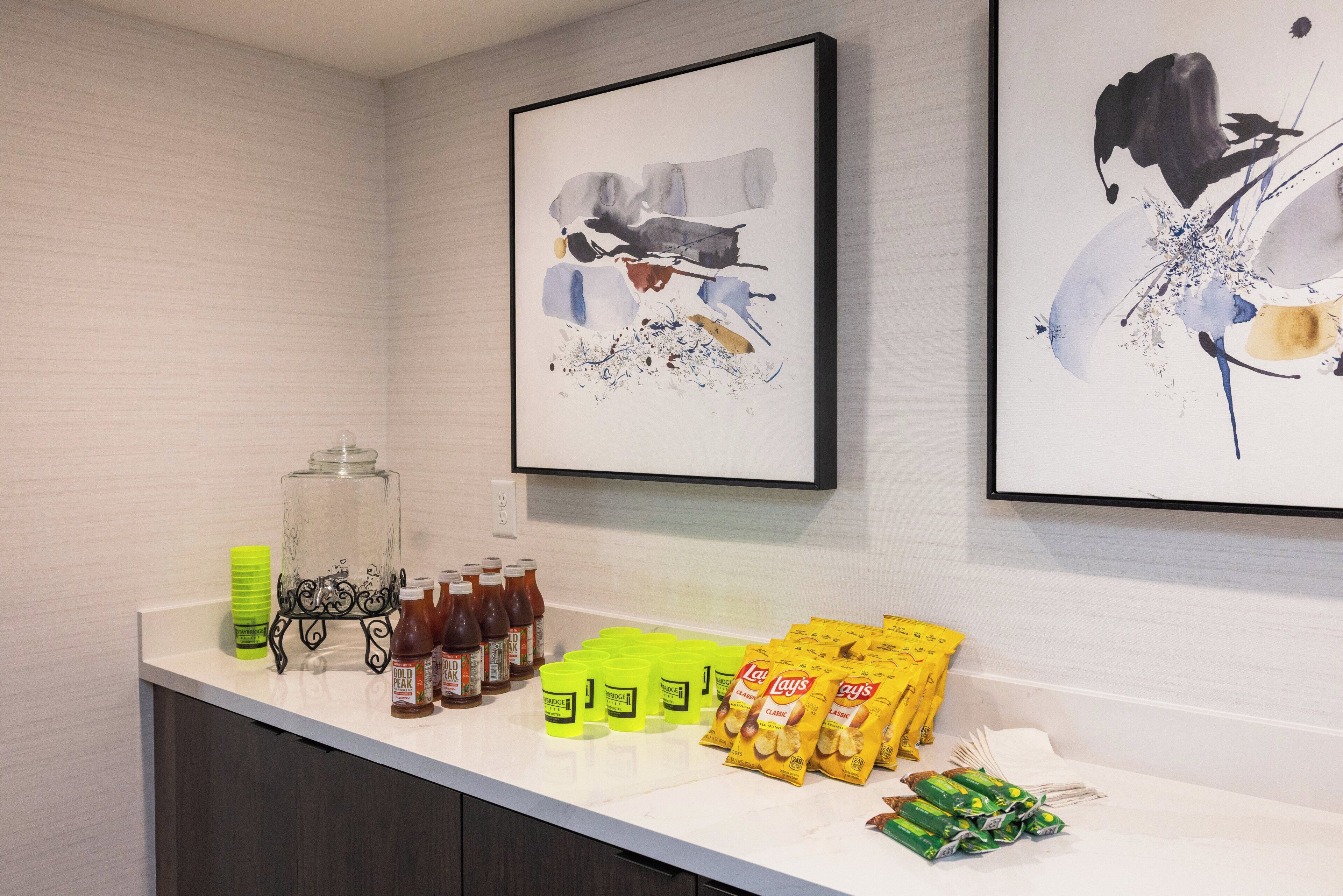 Un espace d’accueil d’hôtel avec un comptoir où sont exposées des boissons, des en-cas et un récipient en verre décoratif.