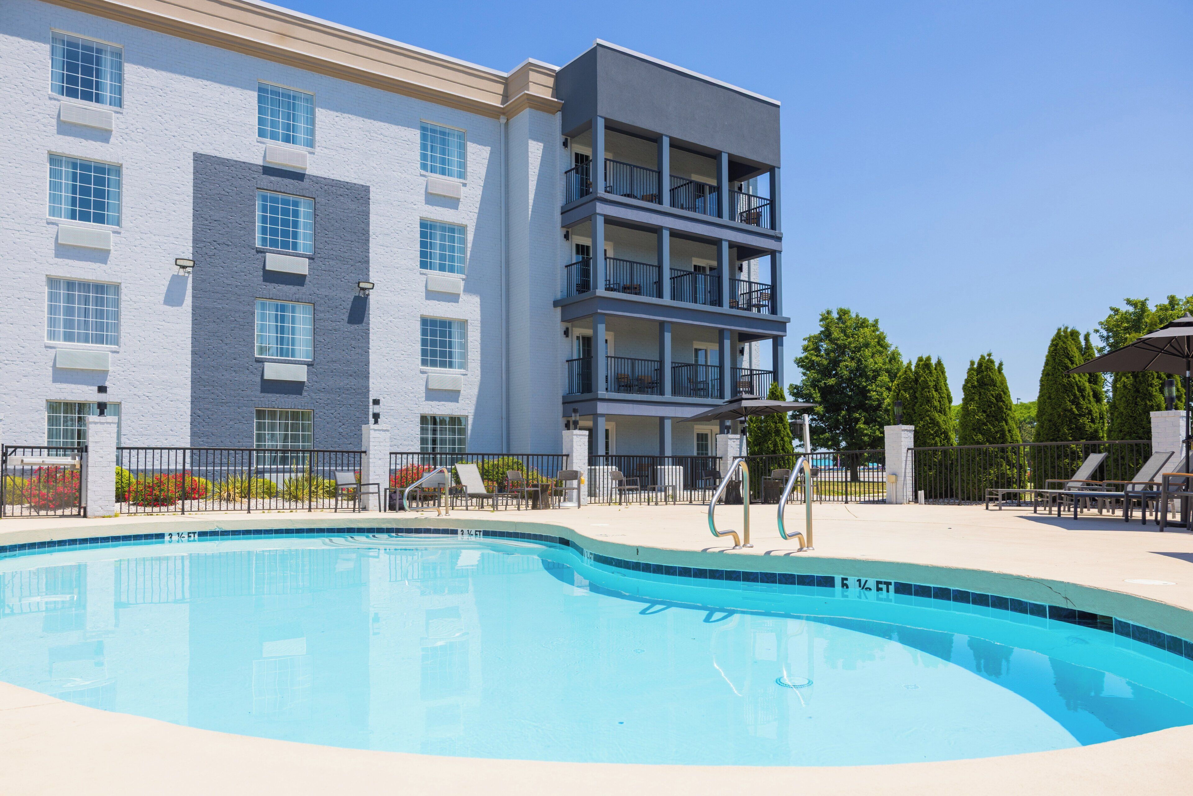 A swimming pool with a clear blue water edge, surrounded by a fence.
