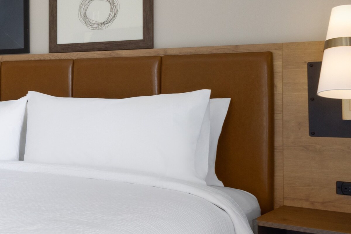 A bed with a wooden headboard and a nightstand with a lamp.