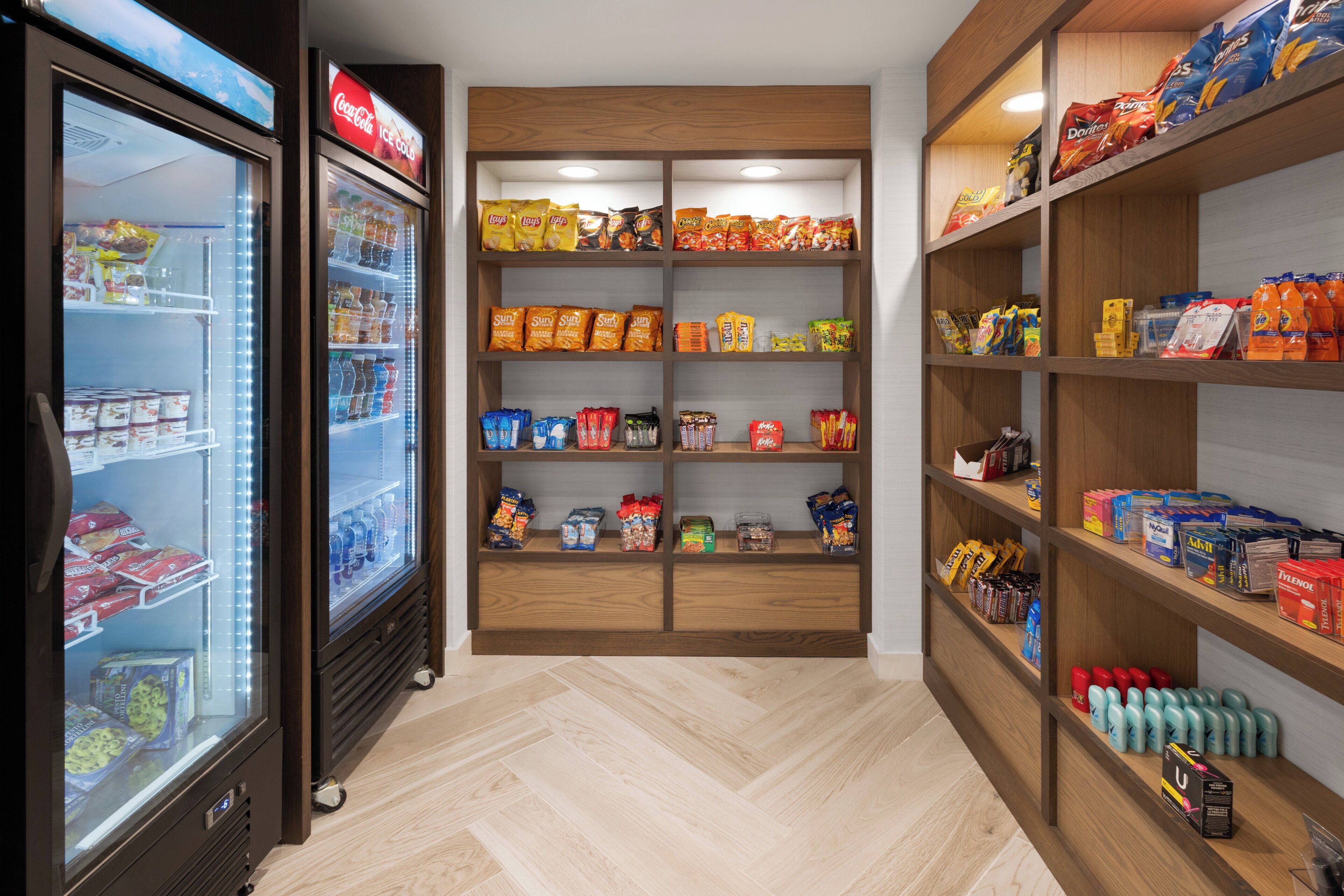 A snack and beverage display area with shelves stocked with various snacks and drinks, including chips, bottled water, and soda.
