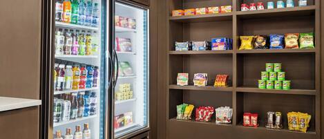 Un mostrador refrigerado con diversas bebidas y aperitivos.