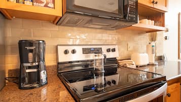 A kitchen with a microwave, stove, coffee maker, and various kitchen items on the counter.