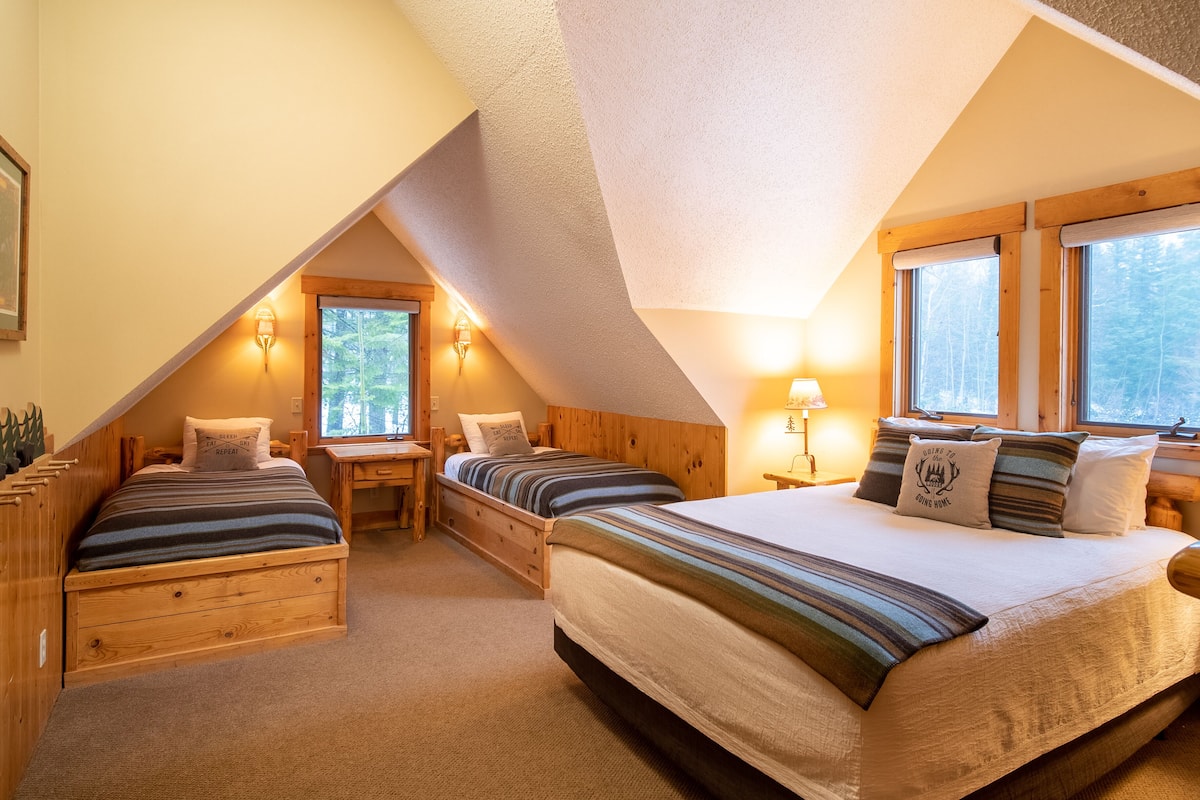 Une chambre confortable située sous les toits, avec deux lits, un bureau et une fenêtre.