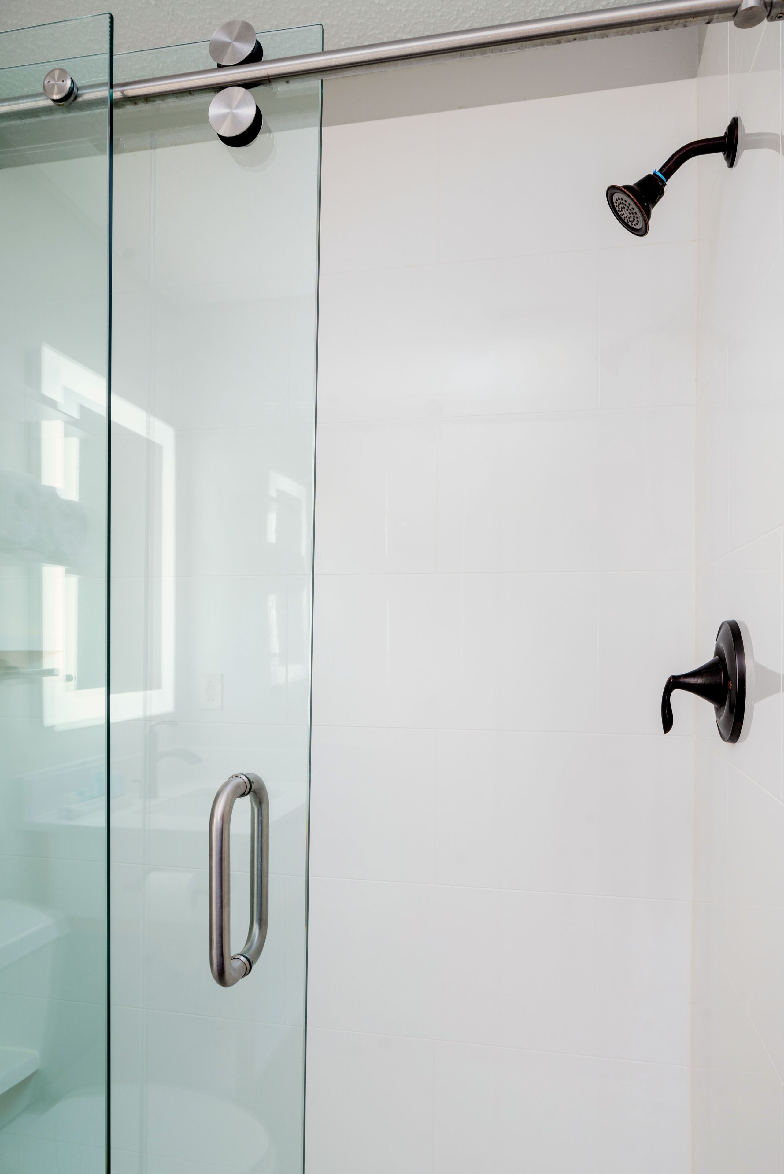 A glass-enclosed shower with a handheld showerhead and a wall-mounted faucet.