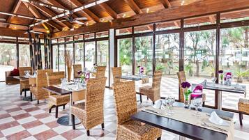 A restaurant with wicker chairs and tables, large windows, and a checkered floor.