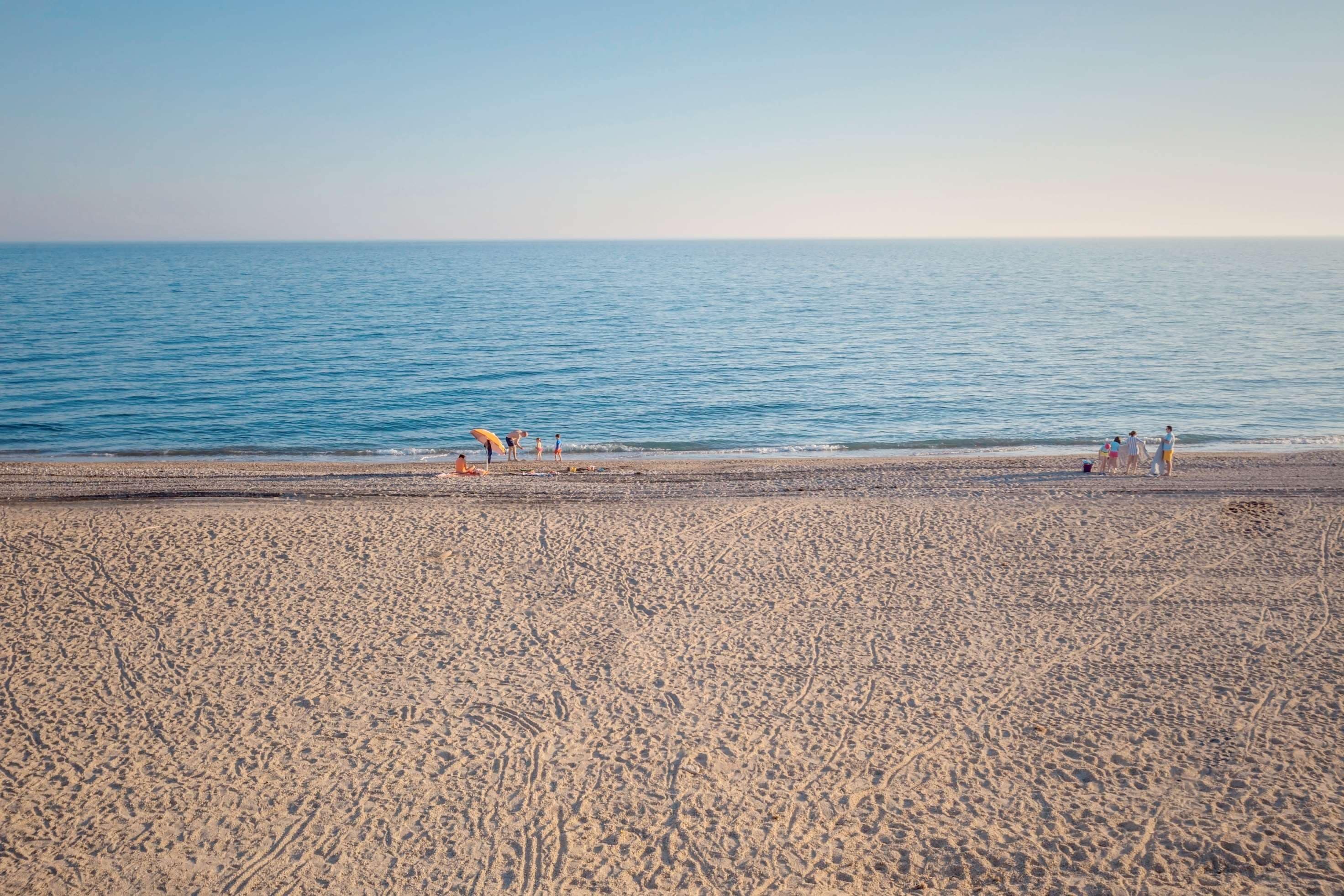 Ein Strand mit weitem Sandbereich und ruhiger See.