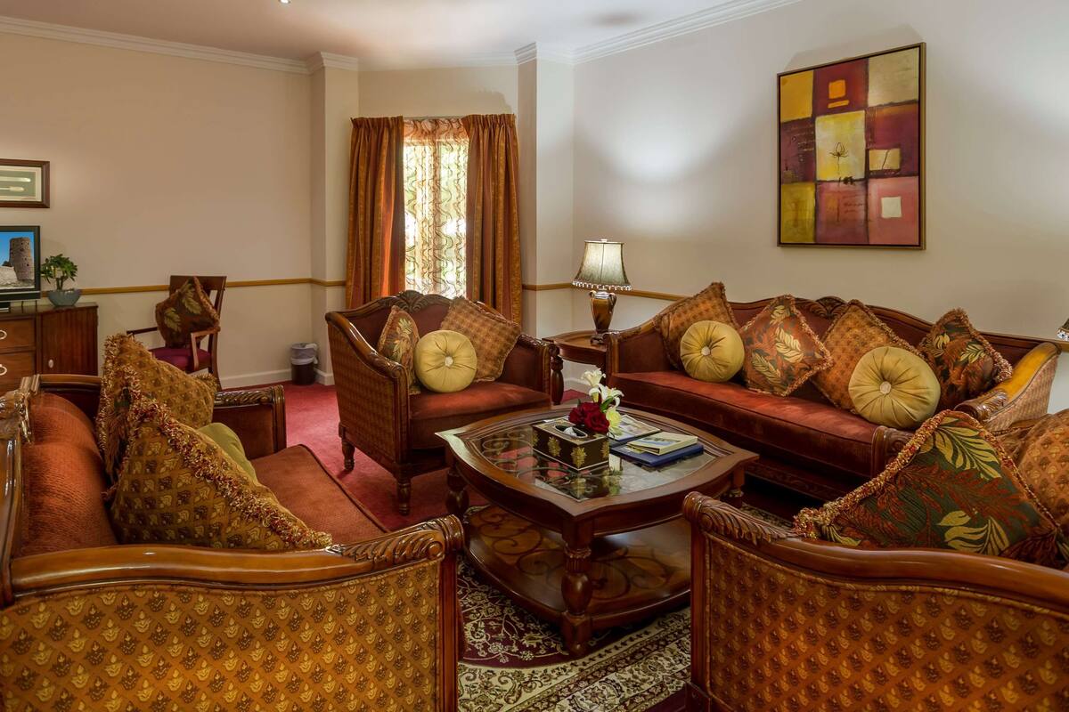 A traditional living room with a sofa set, a coffee table, and a television on a wooden cabinet.