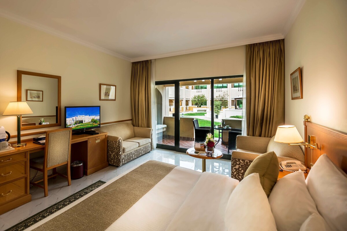 Une chambre d’hôtel équipée d’un lit, d’un bureau, d’une chaise, d’une télévision et offrant une vue sur la cour.