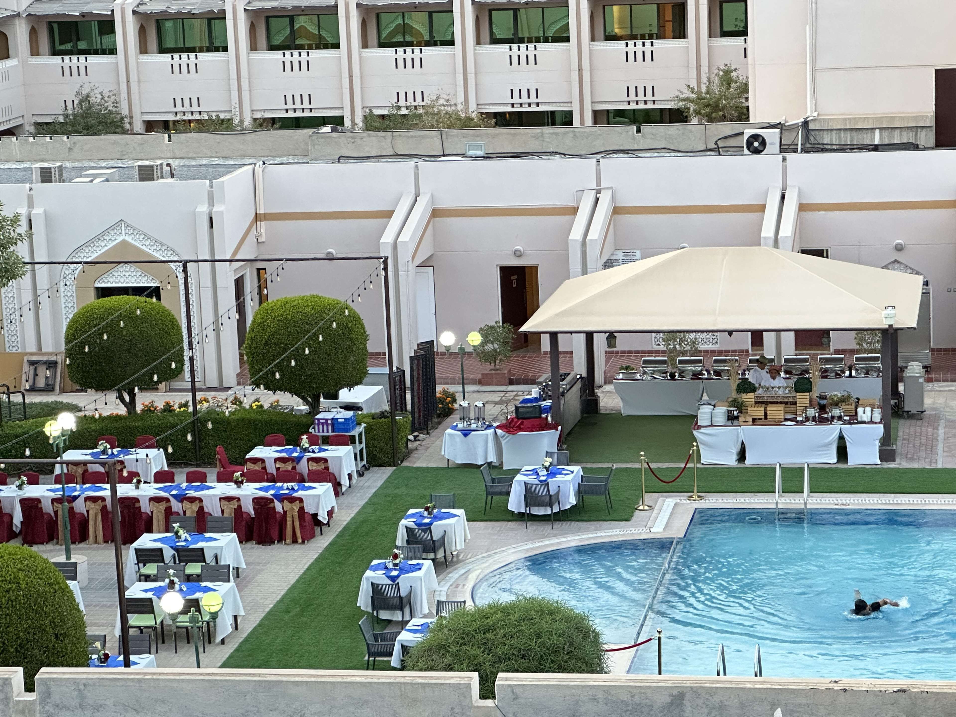 A hotel with outdoor dining areas, a pool, and a covered seating area.
