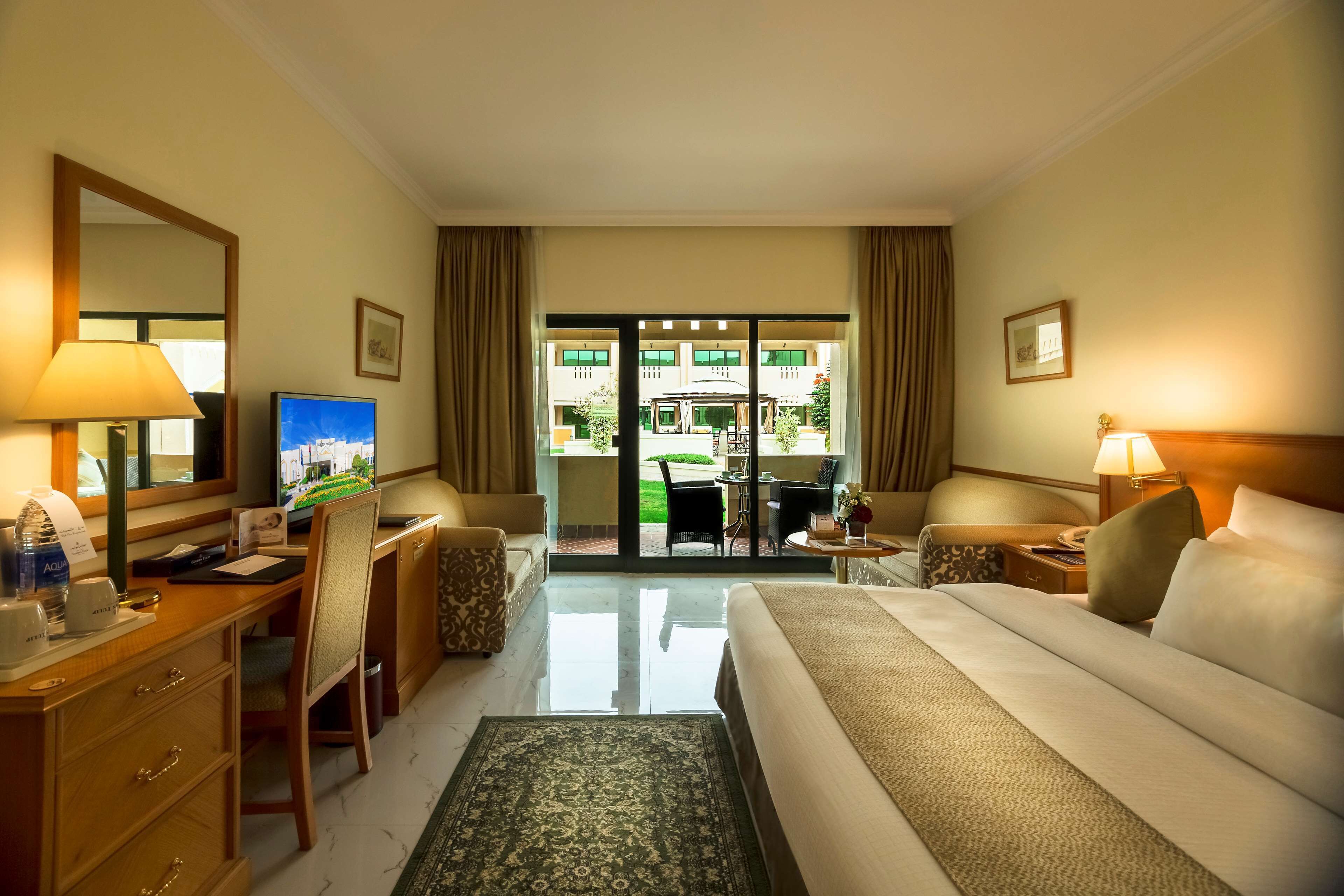 Ein Hotelzimmer mit Bett, Schreibtisch, Stuhl und Blick auf den Innenhof des Hotels.